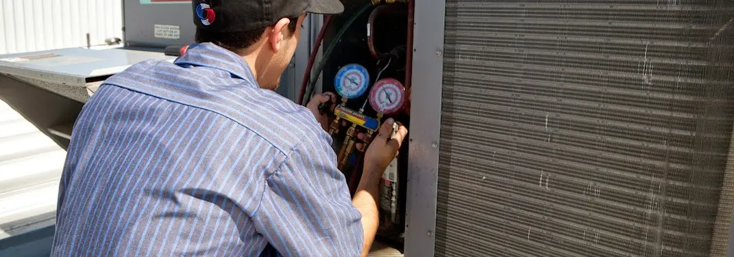 HVAC technician servicing a condenser unit in Lighthouse Point